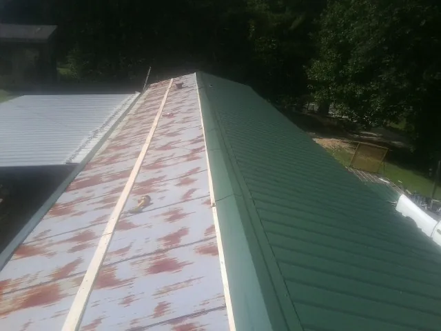 Old rusted panels beside newly installed green metal roofing — Wind Damage Roof Repair by Roofing Brothers in Lester Prairie