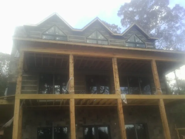 Dormers and porch framing on a large log home under construction — Roof Coating work by our crew in Lester Prairie