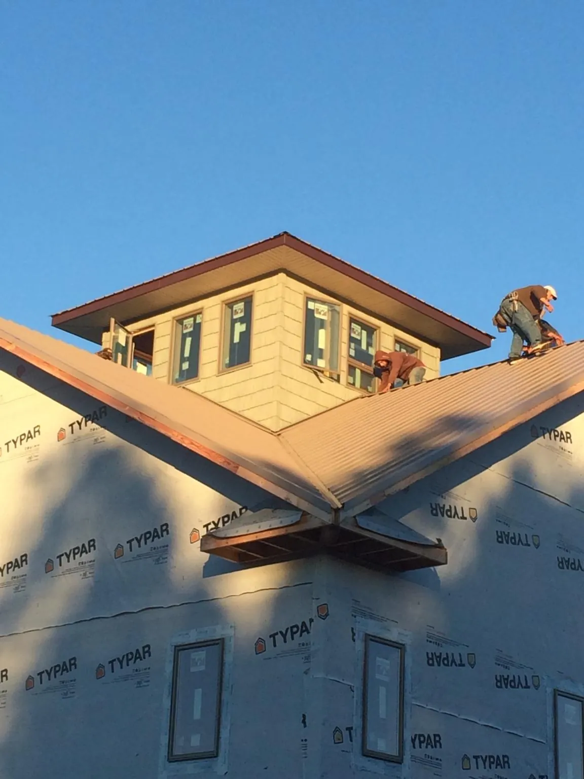 Roofers working around a rooftop cupola on a new metal roof at sunset — Roof Waterproofing in Lester Prairie by Roofing Brothers